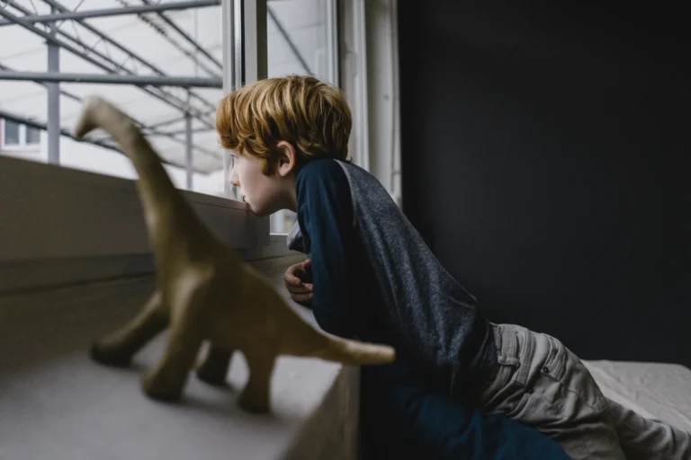 Un ragazzino guarda l'infinito dalla finestra mostrando uno stato di solitudine e di depressione