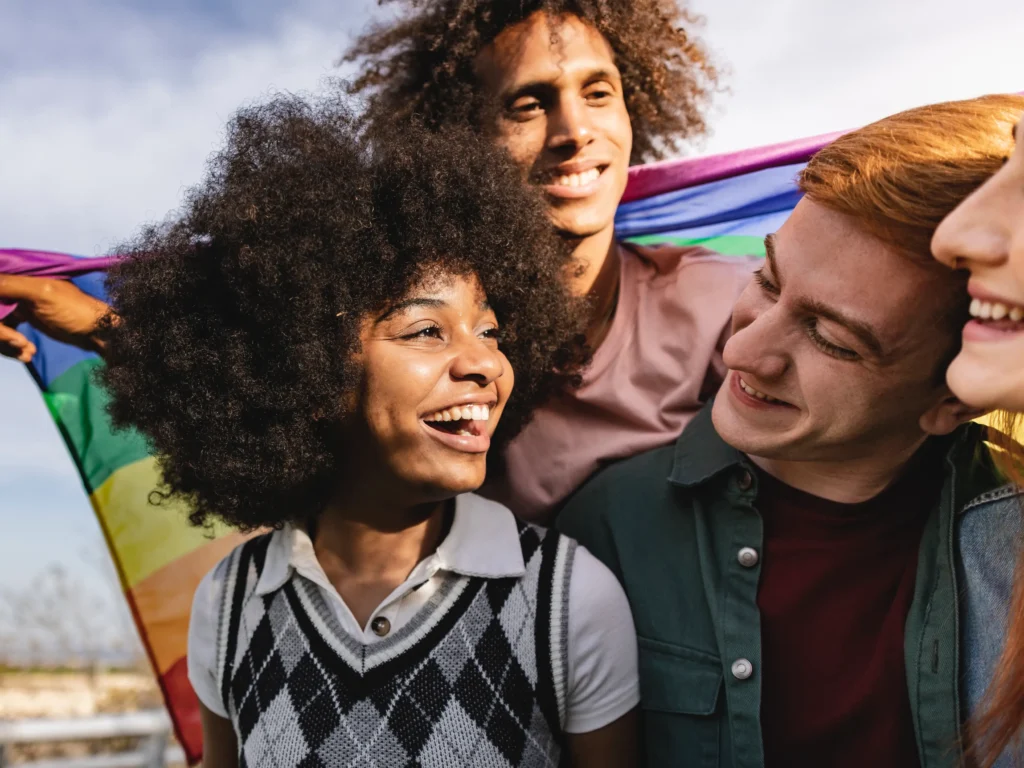 immagine di un gruppo di ragazzi con la bandiera arcobaleno, simbolo della comunità LGBT+. comprendere lo spettro dell'identità sessuale, articolo di Psicologia Sana