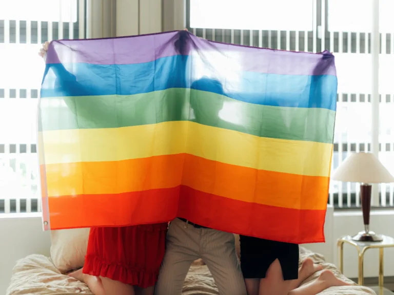 gruppo di ragazzi che si abbracciano dietro alla bandiera arcobaleno lgbt+. La sessualità fluida comprendere e abbracciare la diversità, articolo di Psicologia Sana