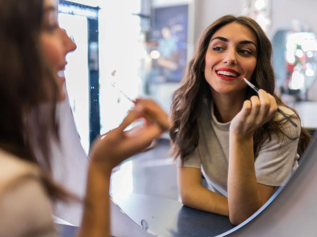 donna allegra che si osserva allo specchio per truccarsi, l'importanza della salute e del benessere sessuale per le donne, articolo di Psicologia Sana