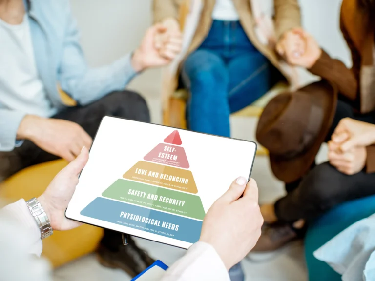 psicologo che spiega ad un gruppo di persone lo schema dei bisogni, la piramide di Maslow, articolo di Psicologia Sana